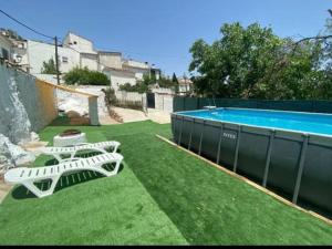 two white chairs sitting on the grass next to a swimming pool at CasaBenadalid. Casa rural con piscina. in Benadalid