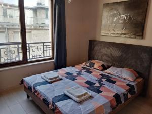 um quarto com uma cama com uma colcha e uma janela em 3 стаен апартамент идеален център Варна em Varna City