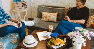 a group of three women sitting in a living room at Karma Chalets in Gurgaon