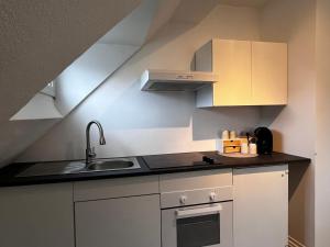 a kitchen with white cabinets and a sink at FlattyOne Ruhrgebiet - Schlafkomfort und Anbindung - neu renoviert in Bochum