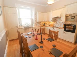 a kitchen with a wooden table and a kitchen with white cabinets at 3 Forest House in Penrith