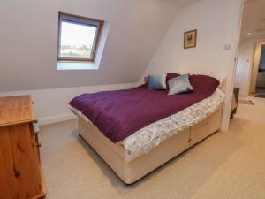 een slaapkamer met een bed met paarse lakens en een raam bij The Chicken Coop in Shrewsbury