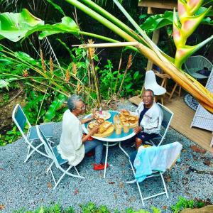 Un groupe de trois personnes assises autour d'une table avec des donneurs dans l'établissement Propriete d'une chambre avec wifi a Petit Bourg a 4 km de la plage, à Petit-Bourg