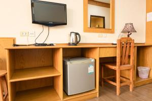 een kamer met een bureau, een televisie en een koelkast bij RoomQuest Golden Triangle Premium Collection in Chiang Saen
