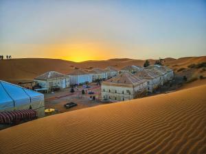 un grupo de edificios en el desierto con la puesta de sol en Merzouga Tents © Official en Merzouga