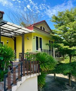 a yellow house with a fence in front of it at Villa Patong in Ban Na Nai