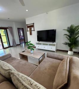 a living room with a couch and a flat screen tv at Villa Patong in Ban Na Nai