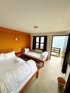 1 dormitorio con 2 camas y ventana grande en Hill Top Lodge Ghandruk, en Astam