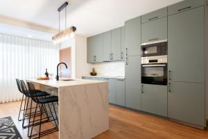 a kitchen with white cabinets and a island with a sink at Sophisticated Modern Flat - Ace Location in Porto