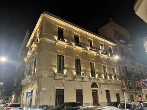 un gran edificio blanco con coches estacionados frente a él en Loft In Master Palace, en Catania