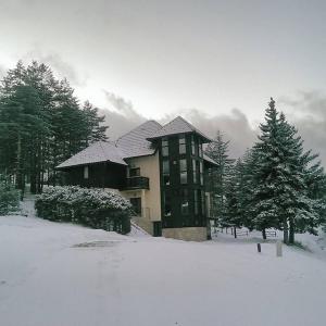 a large building with snow on it in a yard at Vila Zabac - Ski Center Tornik in Zlatibor