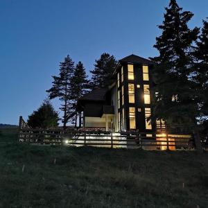 una casa grande con luces encendidas en un campo en Vila Zabac - Ski Center Tornik en Zlatibor