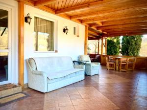 a porch with a couch and chairs and a table at Pensiunea Casa-Stefanel in Sadova