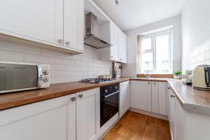 a kitchen with white cabinets and a microwave at The Angel Collection in London