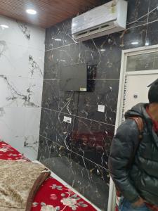 człowiek stojący w pokoju ze ścianą w obiekcie Elite hotel w mieście Ujjain
