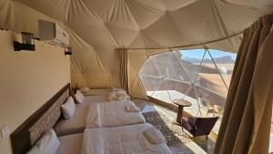a room with three beds in a tent with a window at Sama Rum Camp in Wadi Rum