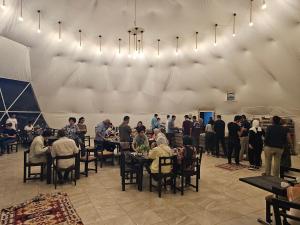 un grupo de personas sentadas en mesas en una habitación en Sama Rum Camp en Wadi Rum