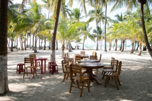 un grupo de mesas y sillas en una playa con palmeras en Coral Paradise Beach Resort, Lakshadweep, en Agatti