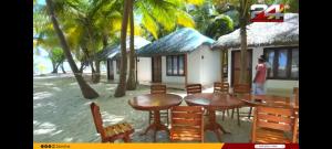 um homem parado em frente a uma casa com mesas e cadeiras em Coral Paradise Beach Resort, Lakshadweep em Agatti