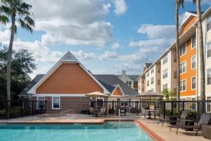 een zwembad in een hotel met stoelen en palmbomen bij Residence Inn by Marriott Orlando East/UCF Area in Orlando