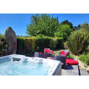 a hot tub in a yard with chairs and a table at La Maison Keribin in Moëlan-sur-Mer