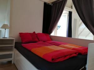 Una cama con sábanas rojas y naranjas y una ventana en De Oude Zeilmakerij, groot, sfeervol vakantiehuis., en Woudsend
