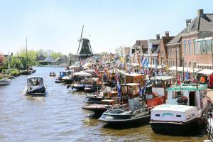 un grupo de barcos están atracados en un canal en De Oude Zeilmakerij, groot, sfeervol vakantiehuis., en Woudsend