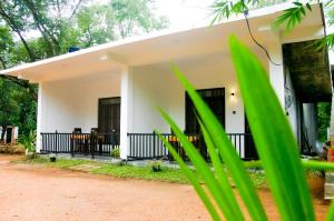 een wit huis met groene planten op de voorgrond bij Sigiri Heaven Villa in Sigiriya