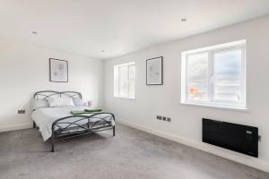 a white bedroom with a bed and a flat screen tv at Luxurious 3-Bed Penthouse in Sheffield in Handsworth