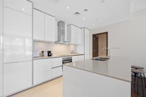 Spacious 2 Bedroom Luxury Apartment, City Walk Dubai في دبي: مطبخ أبيض مع دواليب بيضاء ومغسلة