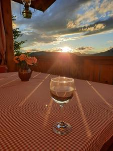 a glass of wine sitting on a table with the sunset at Haus Rigl in Schladming