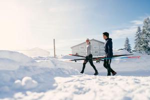 Twee mannen die met hun ski's door de sneeuw lopen. bij Valbella Resort in Valbella