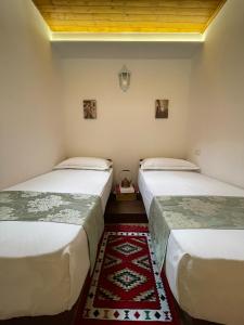 twee bedden in een kamer met een tapijt ertussen bij The Well House - UNESCO in Berat