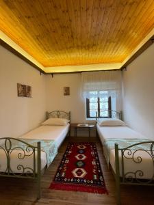 two beds in a room with a wooden ceiling at The Well House - UNESCO in Berat