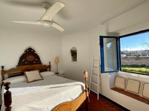 a bedroom with a bed with a ceiling fan and a window at MASIA CENTENARIA EN SITGES in Sitges