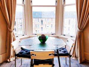 a dining room with a table and chairs and windows at Glen Self-catering Apartment in Port Glasgow