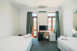 1 dormitorio con 2 camas y escritorio con ordenador en Newtown Cozy Stays en Sídney