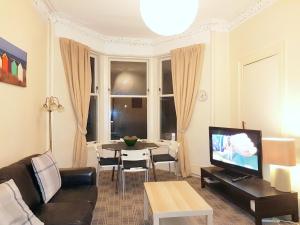 een woonkamer met een bank en een tafel bij Glen Self-catering Apartment in Port Glasgow