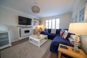 a living room with a blue couch and a tv at Trelowen in Padstow