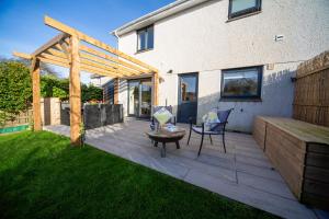 a patio with a table and a wooden pergola at Trelowen in Padstow