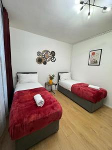 a bedroom with two beds with red covers in it at Kings Cross-Euston Apartment in London