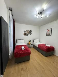 a bedroom with two beds with red covers and a window at Kings Cross-Euston Apartment in London