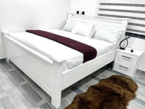 a white bed in a bedroom with a brown rug at Kemc Apartment in Ashalebotwe