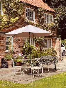 stół i krzesła z parasolem przed domem w obiekcie Characterful Yorkshire cottage, beautiful views w mieście York