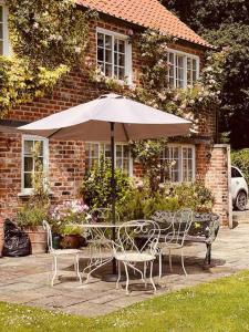 a table and chairs with an umbrella in front of a house at Characterful Yorkshire cottage, beautiful views in York