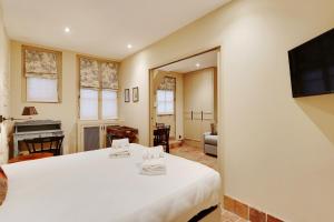 a bedroom with a large white bed and a living room at Pick A Flat's Apartments in Saint Germain - Paul-Louis Courier in Paris
