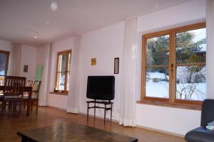 a living room with a tv and a table and windows at Ferienhaus-Eschenlohe-Direkt-in-Bergnaehe-Wanderungen-und-Mountainbike-vom-Haus-aus-moeglich in Eschenlohe