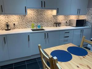 a kitchen with blue cabinets and a wooden table at Wood Green Budget Rooms - Next to Mall & Metro Station - 10 Min to City Center in London