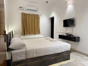 1 dormitorio con 2 camas y TV de pantalla plana en La Tamara Suite, en Pondicherry