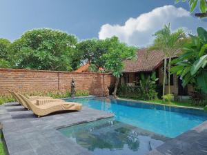 una piscina frente a una casa con una pared de ladrillo en Mahe Garden Inn and Villas by Kamara, en Kuta